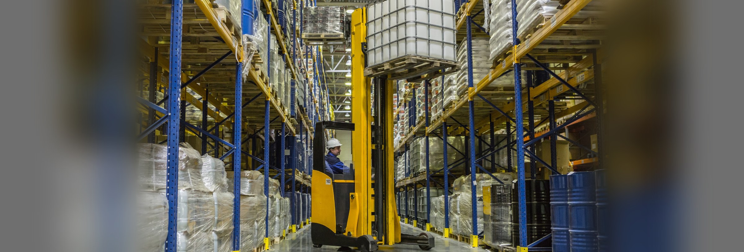 A forklift operator at work in a large warehouse.